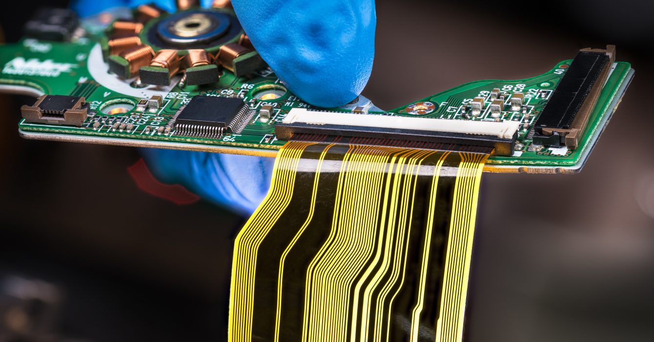 Flat plastic strip flexible cable on printed circuit board on a dark background